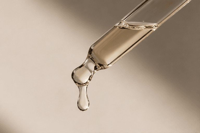 Close-up of a glass dropper with a golden droplet — clarity and formulation detail