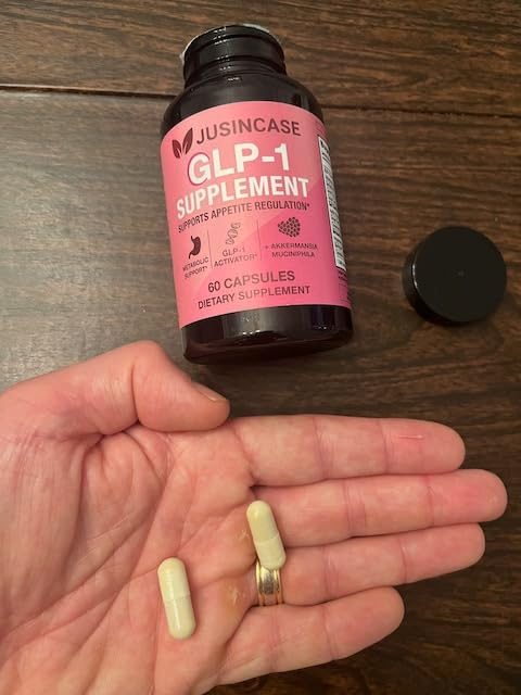 Hand holding two JUSINCASE GLP-1 Supplement capsules next to the bottle